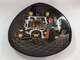 a black plate with a picture of a man and a woman in front of a fireplace