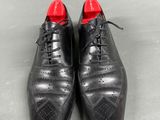 a pair of black shoes with red soles on a gray surface