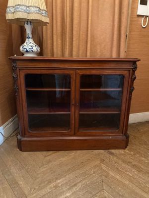 une armoire en bois avec des portes vitrées et une lampe posée dessus