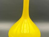 yellow glass vase sitting on a table against a gray background