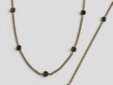 un gros plan sur un collier à chaîne en or orné de perles noires