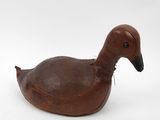 an old wooden duck sitting on top of a white surface