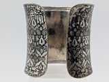 a close up of a silver cuff bracelet on a clear surface