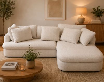 a white couch with pillows and a table with a potted plant on it