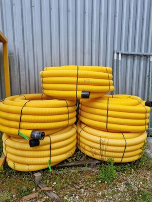 un tas de tuyaux jaunes posés au milieu d'un champ recouvert d'herbe