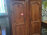 a wooden armoire in a room with a table and chairs