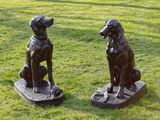 two statues of dogs sitting on a skateboard in the grass