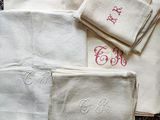 several white towels with embroidered monograms on them on a rug