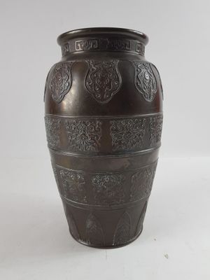 un vase brun posé sur une surface blanche