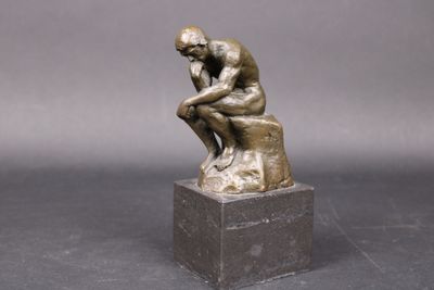 une statue en bronze d'un homme assis sur un rocher