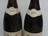 two bottles of red wine sitting next to each other on a table