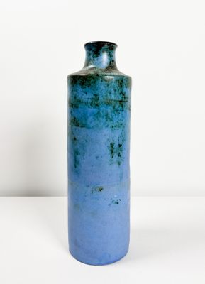 un vase bleu posé sur une table blanche