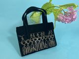 black velvet handbag with gold threadwork and flowers on a blue background