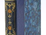 un vieux livre à la couverture bleue posé sur une surface blanche