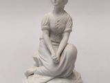 une statue blanche représentant une femme assise sur un socle