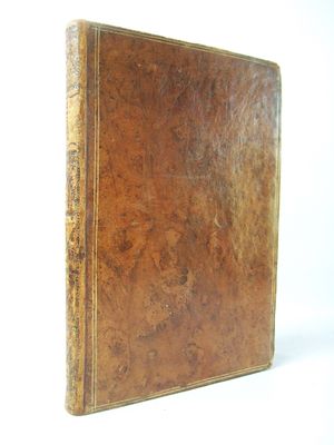 an old brown book sitting on top of a white surface