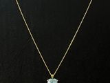 un collier plaqué or orné d'un pendentif en topaze bleue