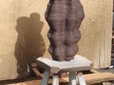un grand vase marron posé sur un tabouret devant un mur