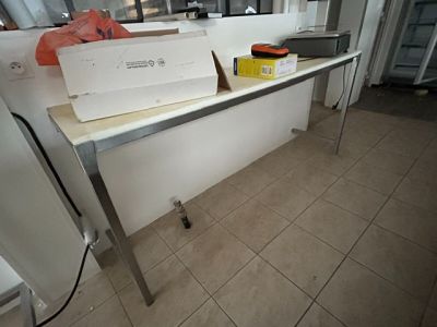 un ordinateur portable posé sur une table dans une cuisine où se trouve un réfrigérateur