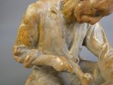 une figurine représentant un homme assis par terre