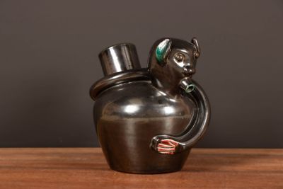 un vase noir orné d'un singe, posé sur une table en bois