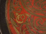 a close up of a red and gold plate with gold designs