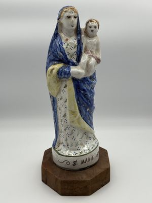 a figurine of a woman holding a child on a wooden base