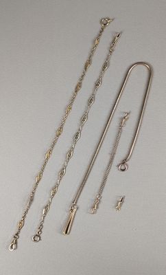 trois colliers en argent et une paire de boucles d'oreilles posés sur une surface blanche