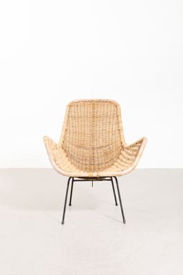 une chaise en rotin avec des pieds noirs et une assise en osier