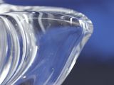 a close up of a clear glass vase with a blue background