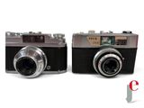 two cameras sitting next to each other on a white surface