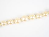 un gros plan d'un collier de perles sur une surface blanche