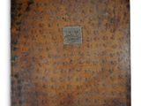 un vieux livre à la couverture brune posé sur une surface blanche