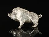 a close up of a silver pig figurine on a black surface
