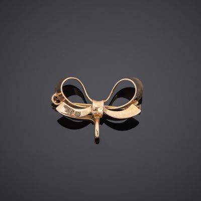a close up of a gold bow brooch on a black surface
