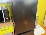 a black refrigerator in a kitchen with a microwave on top of it