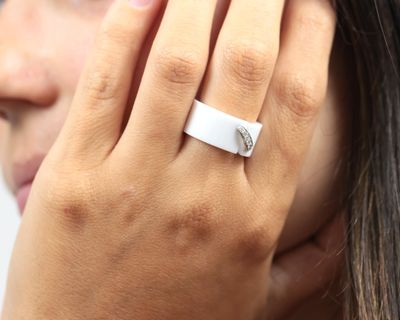 Quelqu'un porte une bague blanche sertie d'un diamant.