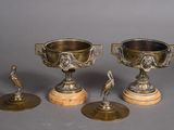 three antique brass trophy cups and a bronze figurine on marble bases