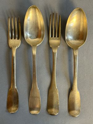 four spoons and a fork are lined up on a table