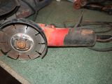 a red and black electric grinder on a green carpet