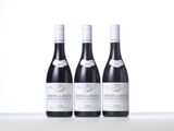 three bottles of red wine are lined up on a table