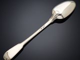 une cuillère ancienne en argent à long manche posée sur une surface noire