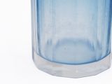 a blue glass vase with a white lid on a white surface