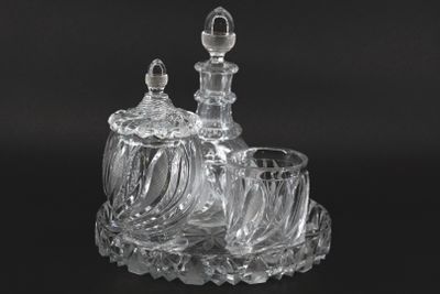 two clear glass decanters and a glass cup on a black surface