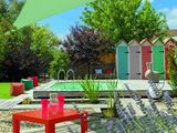 une table rouge posée sur une terrasse en bois près d'une piscine