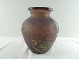 un vase marron orné de motifs dorés, posé sur une table blanche