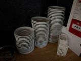 several stacks of white plates stacked on top of each other in front of a black wall