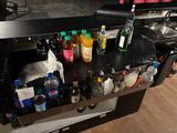 un plan de travail noir sur lequel sont posées des bouteilles d'alcool et des condiments