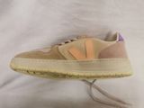 beige and pink sneakers with laces are on a white surface