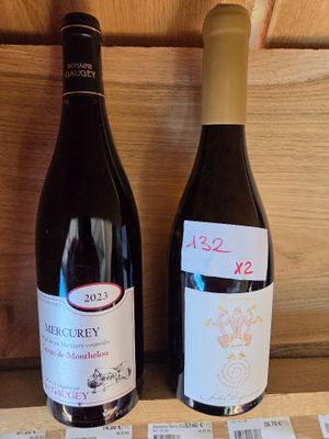 deux bouteilles de vin posées sur une étagère l'une à côté de l'autre